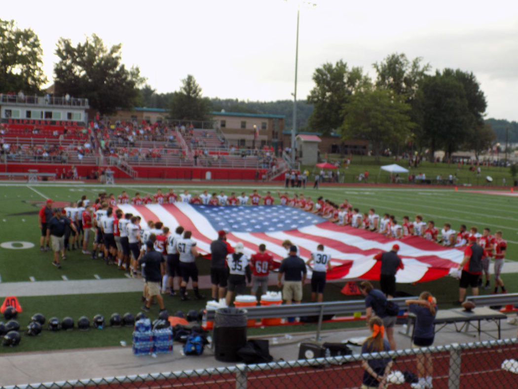 https://clarionsportszone.com/wp-content/uploads/2021/08/Football-2021-0002-Slippery-Rock-players-with-Flag-1050x788.jpg